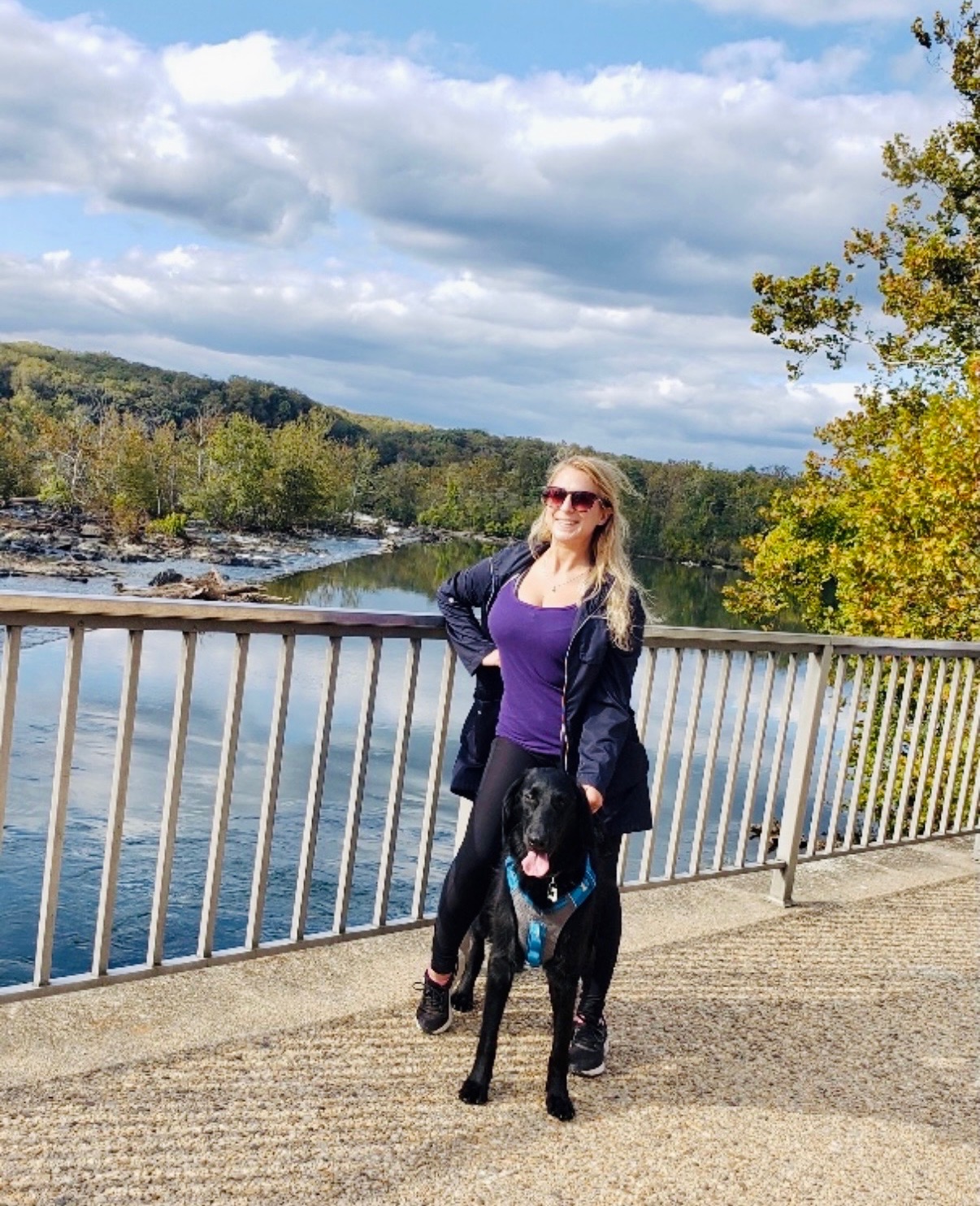 Ashley and a happy black dog on a scenic river overlook